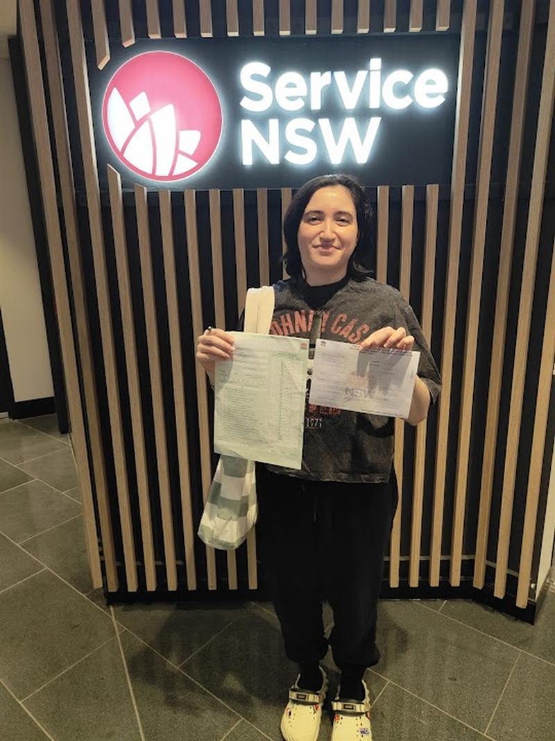 Learner driver holding her passed driving test paperwork at Service NSW